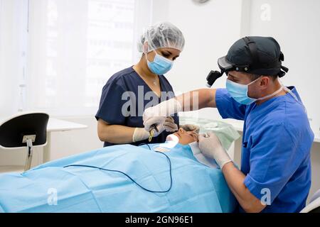 Il chirurgo sutura la palpebra dopo un intervento di chirurgia plastica Foto Stock
