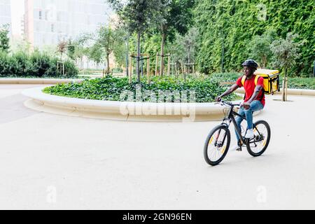 Giovane uomo di consegna che indossa casco ciclismo sul sentiero Foto Stock