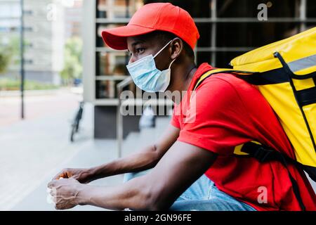 Giovane uomo che indossa maschera protettiva durante COVID-19 Foto Stock