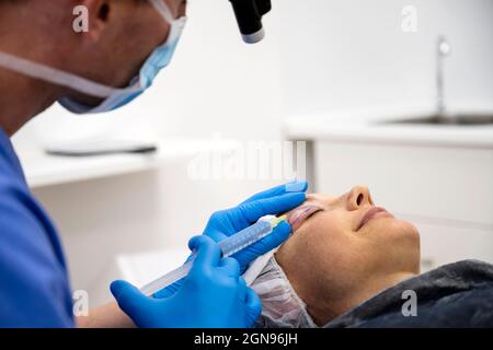 Chirurgo processo di blefaroplastica chirurgia.applicare anestesia in palpebra Foto Stock