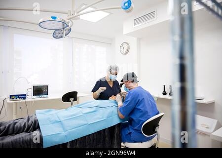 Il chirurgo sutura la palpebra dopo un intervento di chirurgia plastica Foto Stock