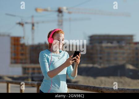 Donna che usa il telefono cellulare mentre ascolta la musica Foto Stock