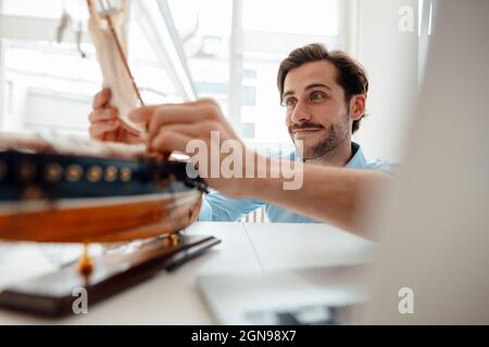 Montante di regolazione uomo d'affari su barca giocattolo in ufficio Foto Stock