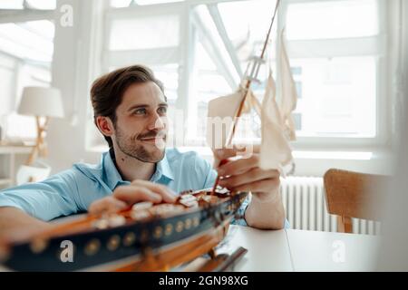 Uomo d'affari maschile che guarda albero su barca giocattolo in ufficio Foto Stock