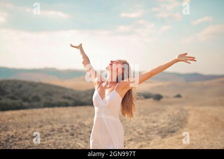 giovane donna a braccia aperte respira aria nella natura Foto Stock