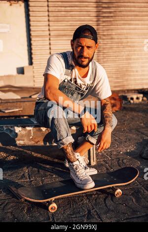 un ragazzo che si appoggia su uno skateboard al tramonto Foto Stock