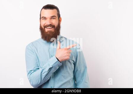 L'uomo sorridente che indossa una maglietta blu chiaro è rivolto da parte su sfondo bianco. Foto Stock