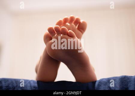 Primo piano ritratto di un ragazzo che mostra i piedi a letto. Foto Stock