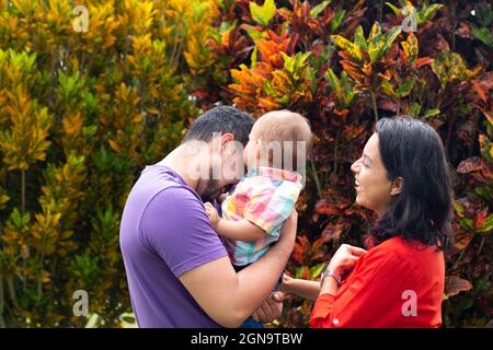 I genitori ridono e abbracciano il loro bambino in autunno. Foto Stock