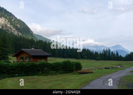 Un villaggio con bella vista sulle Alpi europee in lontananza. Strada tra la natura Foto Stock