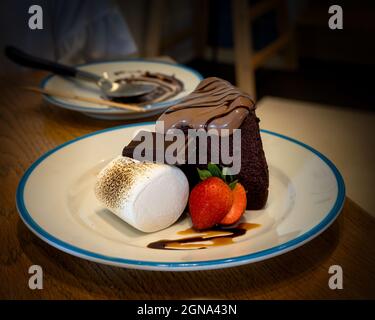 Torta al cioccolato con fragola a fette, marshmallow gigante e un pezzo di cioccolato per dessert. Foto Stock