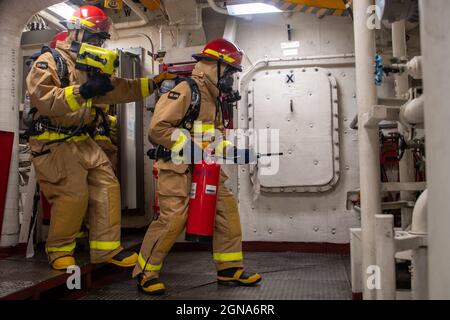 OCEANO PACIFICO (31 agosto 2021) — i marinai entrano nella sala macchine principale durante una trivella antincendio a bordo della nave portuale per il trasporto anfibio USS Portland (LPD 27), 31 agosto. Portland, parte del gruppo USS Essex Amphibious Ready (ARG), insieme all'undicesima unità di spedizione marina (MEU), Opera nell'area di responsabilità della settima flotta statunitense per migliorare l'interoperabilità con alleati e partner e funge da forza di reazione pronta a difendere la pace e la stabilità nella regione dell'Indo-Pacifico. (STATI UNITI Foto Navy di Mass Communication Specialist 2a classe Devin Kates) Foto Stock