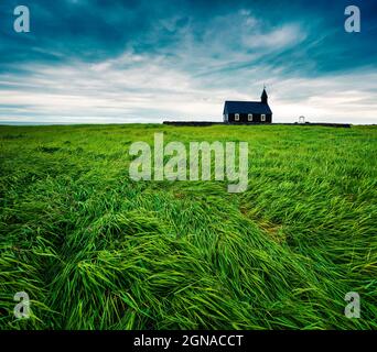 Chiesa di Budakirkja in legno nero a Saefellsnes. Drammatica mattinata estiva con campo di erba verde fresca sulla penisola di Snafellsnes, Islanda occidentale, Euro Foto Stock