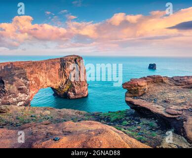 Pittoresca scena serale dell'arco di Dyrholaey. Colorato tramonto estivo nella Riserva Naturale di Dyrholaey, costa meridionale dell'Islanda, Europa. Stile artistico post p Foto Stock