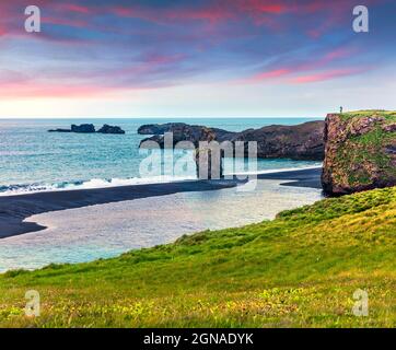Splendida alba estiva nella Riserva Naturale di Dyrholaey con l'uomo solitario sulla roccia. Grande vista dell'arco di Dyrholaey, costa meridionale dell'Islanda, Europa. Artisti Foto Stock