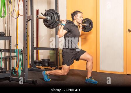 Uomo che fa squat con bar in palestra Foto Stock