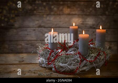 Avvento corona di rami con candele ardenti e decorazione a catena rossa, tradizione nel tempo prima di Natale, rustico sfondo in legno con caldo bo Foto Stock
