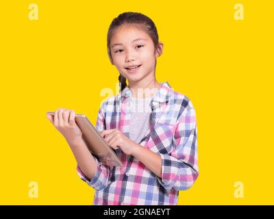 Felice studentessa usando tablet.isolato su sfondo giallo. Foto Stock