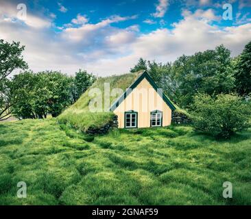 Splendida chiesa in cima al tappeto erboso nel piccolo villaggio Hof. Tramonto colorato a Skaftafell nel Parco Nazionale Vatnajokull, Islanda sud-orientale, Europa. Stile artistico p Foto Stock