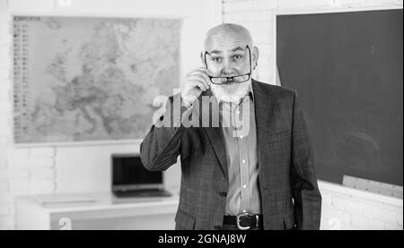 Più strumenti introdotti nelle aule di tutti i giorni. Insegnante di uomo anziano presso la lavagna. Ritorno a scuola. Insegnante di vecchia generazione scolastica. Docente esperto Foto Stock