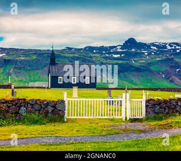 Chiesa di Budakirkja in legno nero a Saefellsnes. Drammatica mattinata estiva con campo di erba verde fresca sulla penisola di Snafellsnes, Islanda occidentale, Euro Foto Stock