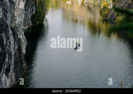 Un uomo che salta da un bungee sopra un canyon nel parco di montagna Ruskeala a Karelia, Russia Foto Stock