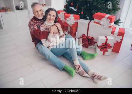 Foto a tutta lunghezza di bella coppia vecchia donna uomo siediti abbraccio con attuale indossare jeans calzini calzini a casa Foto Stock