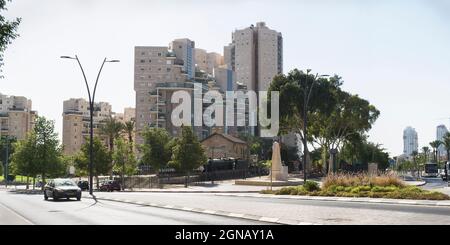 La piccola stazione dei treni Turchi dell'epoca ottomana a Beer Sheva in Israele è circondata da alti edifici moderni e viali con un cielo blu pallido Foto Stock