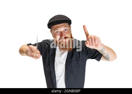 Un elegante uomo, barbiere o tagliacapelli con bearded rosso isolato su sfondo bianco studio. Attrezzi di taglio di supporto. Foto Stock