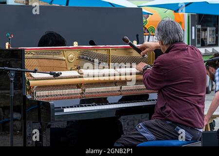 Un sintonizzatore per pianoforte che sintonizza un pianoforte verticale in preparazione di un recital per pianoforte all'aperto. Foto Stock
