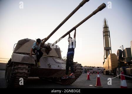 Teheran, Iran. 23 settembre 2021. I ragazzi giocano con un carro armato militare mentre visitano una mostra di guerra che è tenuta e organizzata dal corpo di Guardia rivoluzionaria Islamica (IRGC) in un parco nel sud di Teheran per celebrare l'anniversario della guerra Iran-Iraq (1980-88) il 23 settembre 2021. (Foto di Sobhan Farajvan/Pacific Press) Credit: Pacific Press Media Production Corp./Alamy Live News Foto Stock