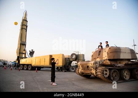 Teheran, Iran. 23 settembre 2021. I ragazzi posano con un carro armato militare mentre visitano una mostra di guerra che è tenuta e organizzata dal corpo di Guardia rivoluzionaria Islamica (IRGC) in un parco nel sud di Teheran per celebrare l'anniversario della guerra Iran-Iraq (1980-88) il 23 settembre 2021. (Foto di Sobhan Farajvan/Pacific Press) Credit: Pacific Press Media Production Corp./Alamy Live News Foto Stock