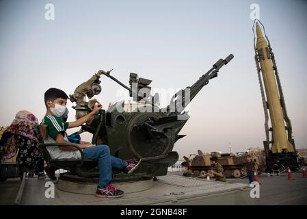 Teheran, Iran. 23 settembre 2021. Giovane ragazzo posa con una pistola anti-aereo mentre visita una mostra di guerra che è tenuto e organizzato dal corpo di Guardia rivoluzionaria Islamica (IRGC) in un parco nel sud di Teheran per celebrare l'anniversario della guerra Iran-Iraq (1980-88) il 23 settembre 2021. (Foto di Sobhan Farajvan/Pacific Press) Credit: Pacific Press Media Production Corp./Alamy Live News Foto Stock