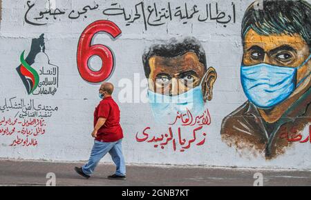 Città di Gaza, striscia di Gaza, Palestina. 23 settembre 2021. Gaza, Palestina. 23 settembre 2021. I palestinesi camminano vicino a un murale raffigurante i 6 prigionieri palestinesi fuggiti dalla prigione di Gilboa il 6 settembre 2021. Anche se Israele ha catturato tutti e sei i prigionieri palestinesi fuggiti dalla prigione di massima sicurezza israeliana, i palestinesi hanno salutato i fuggitivi come eroi nella loro lotta contro l'occupazione israeliana (immagine di credito: © Ahmad Hasaballah/IMAGESLIVE via ZUMA Press Wire) Foto Stock