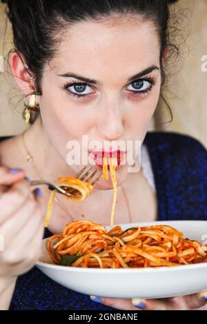 La giovane donna mangia gli spaghetti con salsa di pomodoro Foto Stock