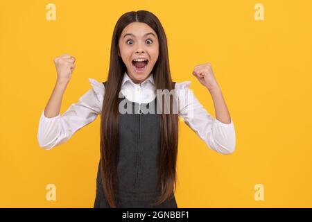 Felice adolescente ragazza vincitore dare il gesto di vittoria celebrando vittoria sfondo giallo, vinto Foto Stock