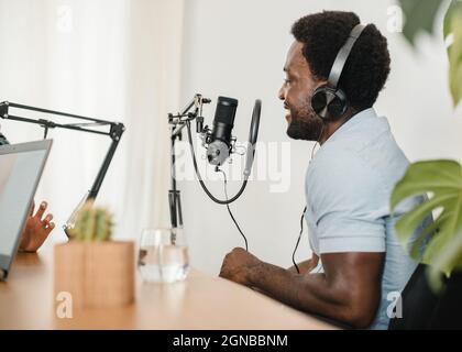 Un uomo nero sorridente che registra podcast con un collega di ritaglio Foto Stock