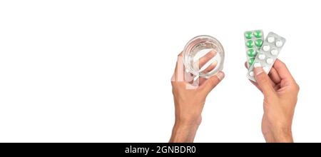 Le mani maschili stanno tenendo confezioni di pillole e un bicchiere d'acqua su un banner bianco. Medicina e trattamento concetto. Vista dall'alto. Foto Stock