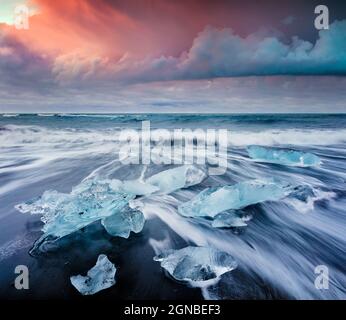 Blocchi di ghiaccio lavati dalle onde sulla spiaggia di Jokulsarlon. Spettacolare alba estiva nel Parco Nazionale Vatnajokull, Islanda sud-orientale, Europa. Stile artistico Foto Stock