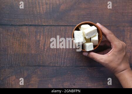 mano dell'uomo che tiene una ciotola di formaggio sul tavolo Foto Stock