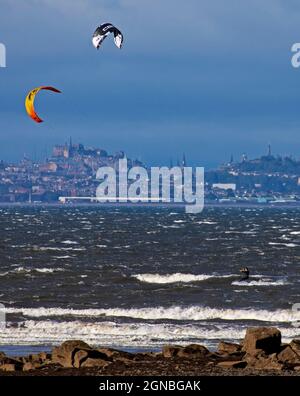 Longniddry, East Lothian, Scozia, tempo britannico. 24 settembre 2021. Buon vento per Kitesurfing anche se molto blustery a W 44 km/h con raffiche 75 km/h sul Firth of Forth. Temperatura 18 gradi centigradi. Nella foto: Alcuni degli appassionati di sport acquatici che sfidano le condizioni difficili con la città di Edimburgo sullo sfondo. Credit: Arch White/Alamy Live News. Foto Stock