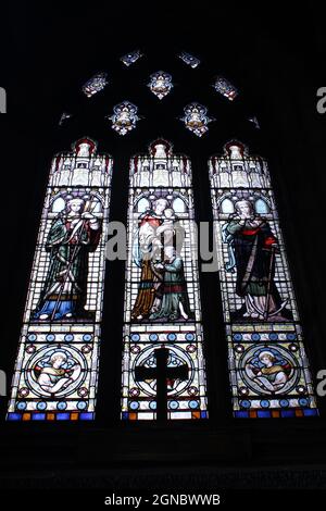 Vetrate colorate di fede speranza e carità all'interno della chiesa di San Tommaso Martire in Up Holland su sfondo nero con spazio copia. Foto Stock