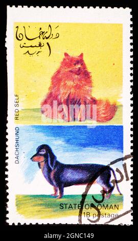 OMAN - CIRCA 1972: Un francobollo dell'Oman che mostra il gatto di auto rosso e il cane di Dachshund Foto Stock