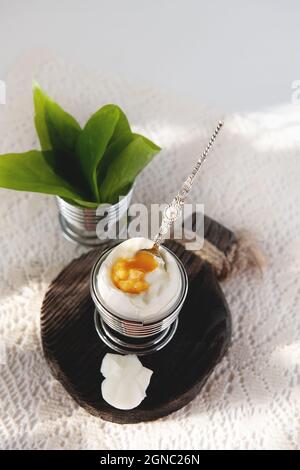 Aprire un uovo sodo in una tazza. Colazione fatta in casa a basso contenuto calorico su un tavolo rustico. Spazio copia Foto Stock