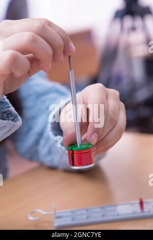 La mano della pupilla ha messo il peso sul barbell fisico primo piano. Uno scolaro svolge un compito sul posto di lavoro. Il concetto di educazione dei bambini, di insegnamento delle conoscenze, delle competenze e delle abilità. Foto Stock