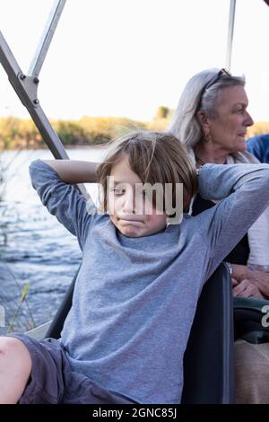 Giovane ragazzo su una barca sul Delta dell'Okavango, Botswana. Foto Stock