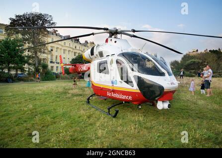 Elicottero Air Ambulance con sede in Sussex nel giardino di Brunswick Square con spettatori, Hove, che partecipano a una chiamata di emergenza. Brighton & Hove, Inghilterra, U.K. Yoga Classe che si tiene sul prato in Brunswick Square Garden, Hove, Brighton & Hove, East Sussex, Engand, REGNO UNITO. Foto Stock