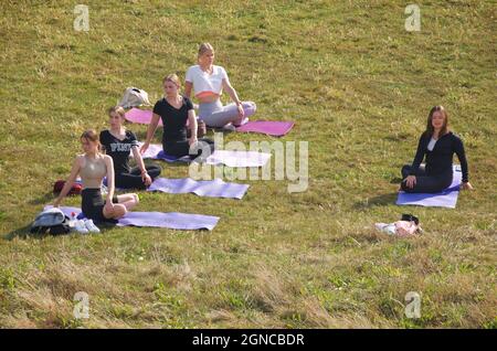 Lezione di yoga tenuto sull'erba in un giardino pubblico, Brighton & Hove, East Sussex, Engerd, Regno Unito. Foto Stock