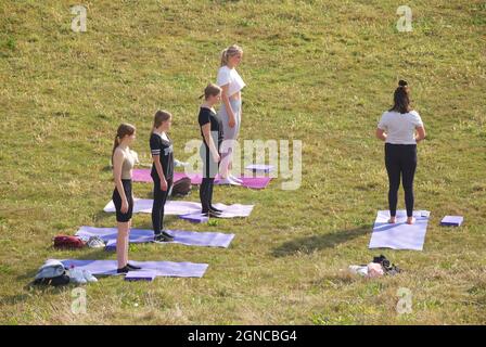 Lezione di yoga tenuto sull'erba in un giardino pubblico, Brighton & Hove, East Sussex, Engerd, Regno Unito. Foto Stock