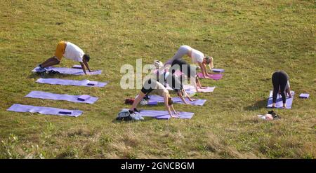Lezione di yoga tenuto sull'erba in un giardino pubblico, Brighton & Hove, East Sussex, Engerd, Regno Unito. Foto Stock
